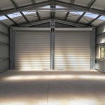 Interior of completed steel shed showing open span, roller doors, and clean structural layout