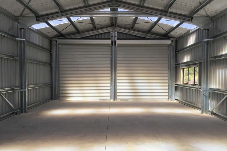 Interior of completed steel shed showing open span, roller doors, and clean structural layout