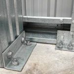 Galvanised steel shed base connection bolted to concrete showing structural bracket and anchor points