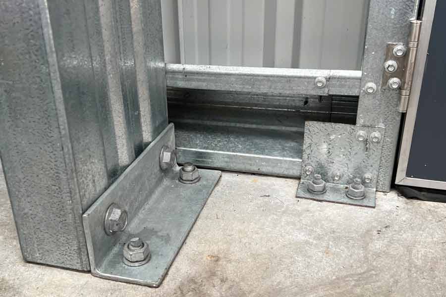 Galvanised steel shed base connection bolted to concrete showing structural bracket and anchor points