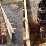 Shed foundation trenching and post hole drilling showing site preparation and concrete layout for a steel shed build